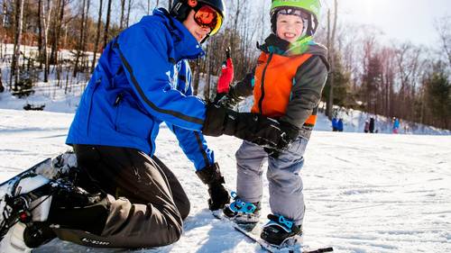 Loon Mountain instructor giving young boy a snowboard lesson