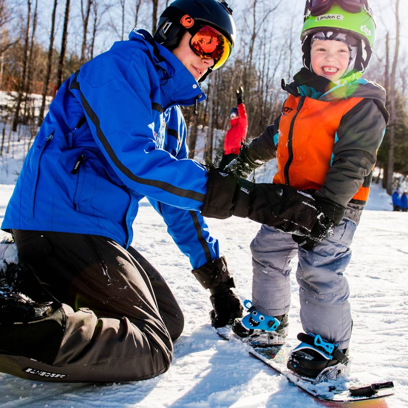child with coach learning to snowboard