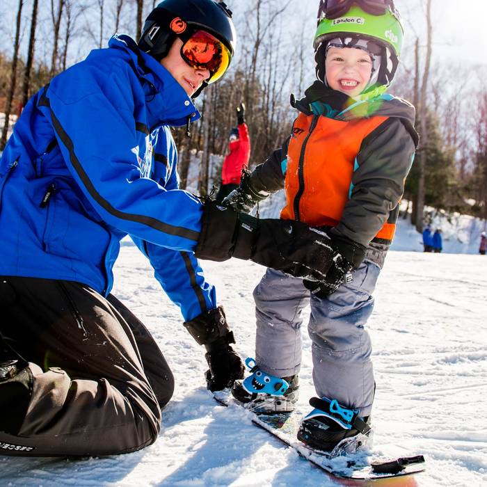 Young boy getting snowboard lesson from Loon Mountain snowsports instructor
