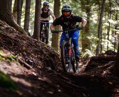 2 bikers going around a berm in the summer