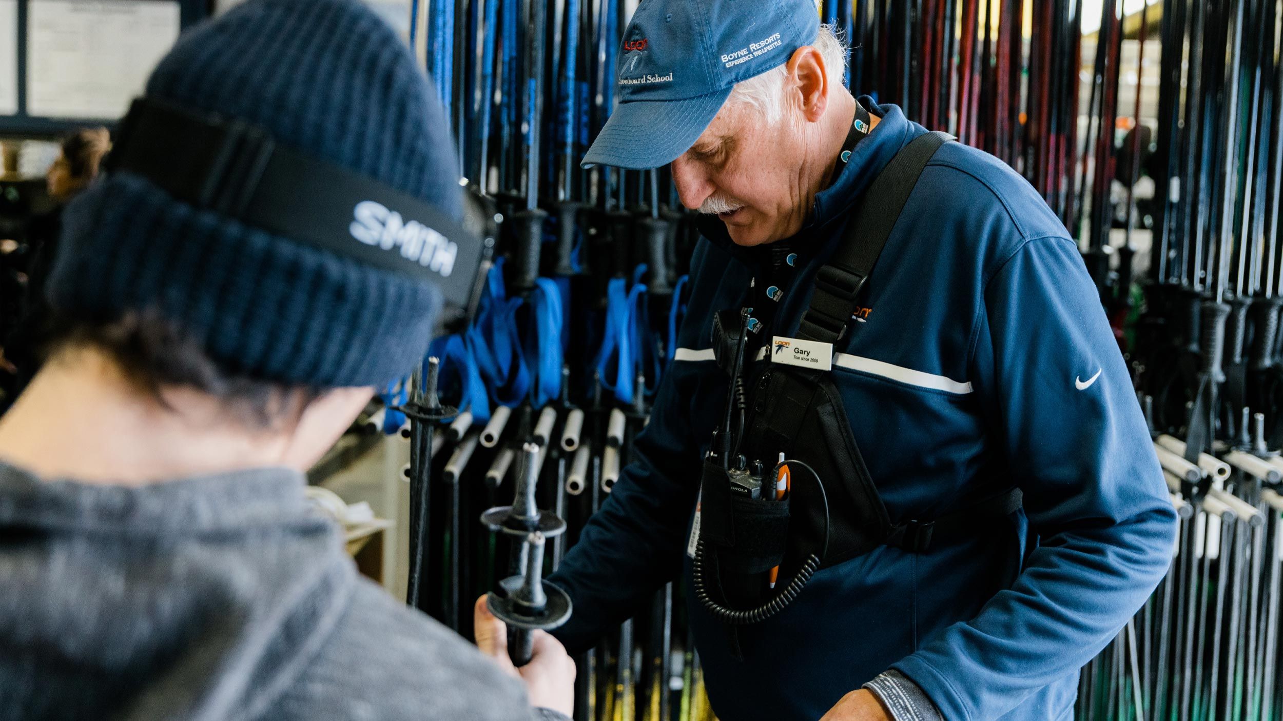 Rental shop assistant helping guest set up rental equipment.
