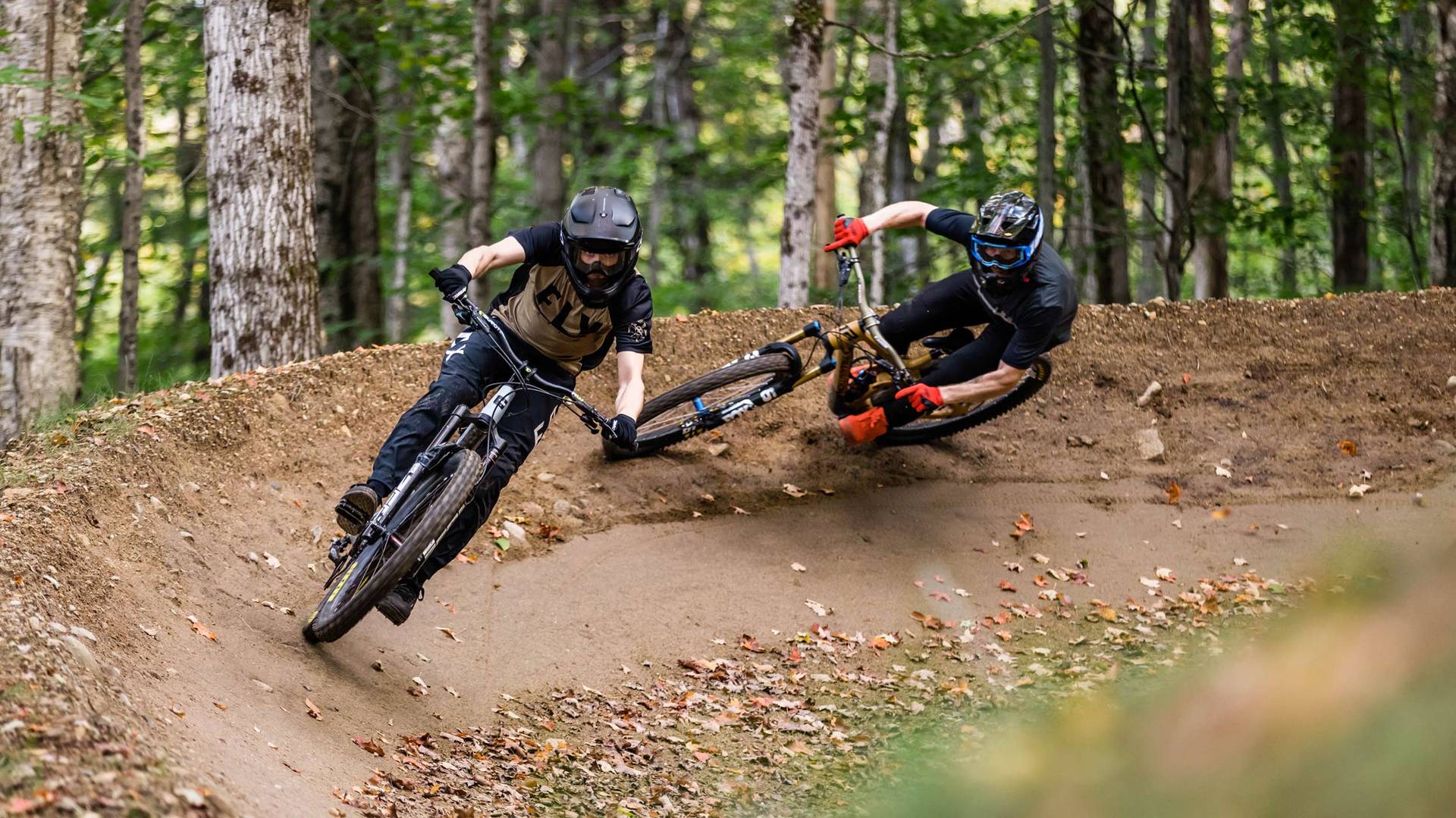 Two mountain bikers on a berm in the fall