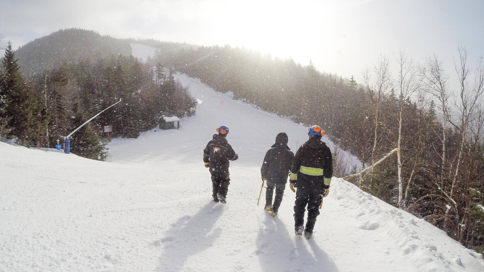 group of snowmakers walking up a winter ski trail at Loon Mountain