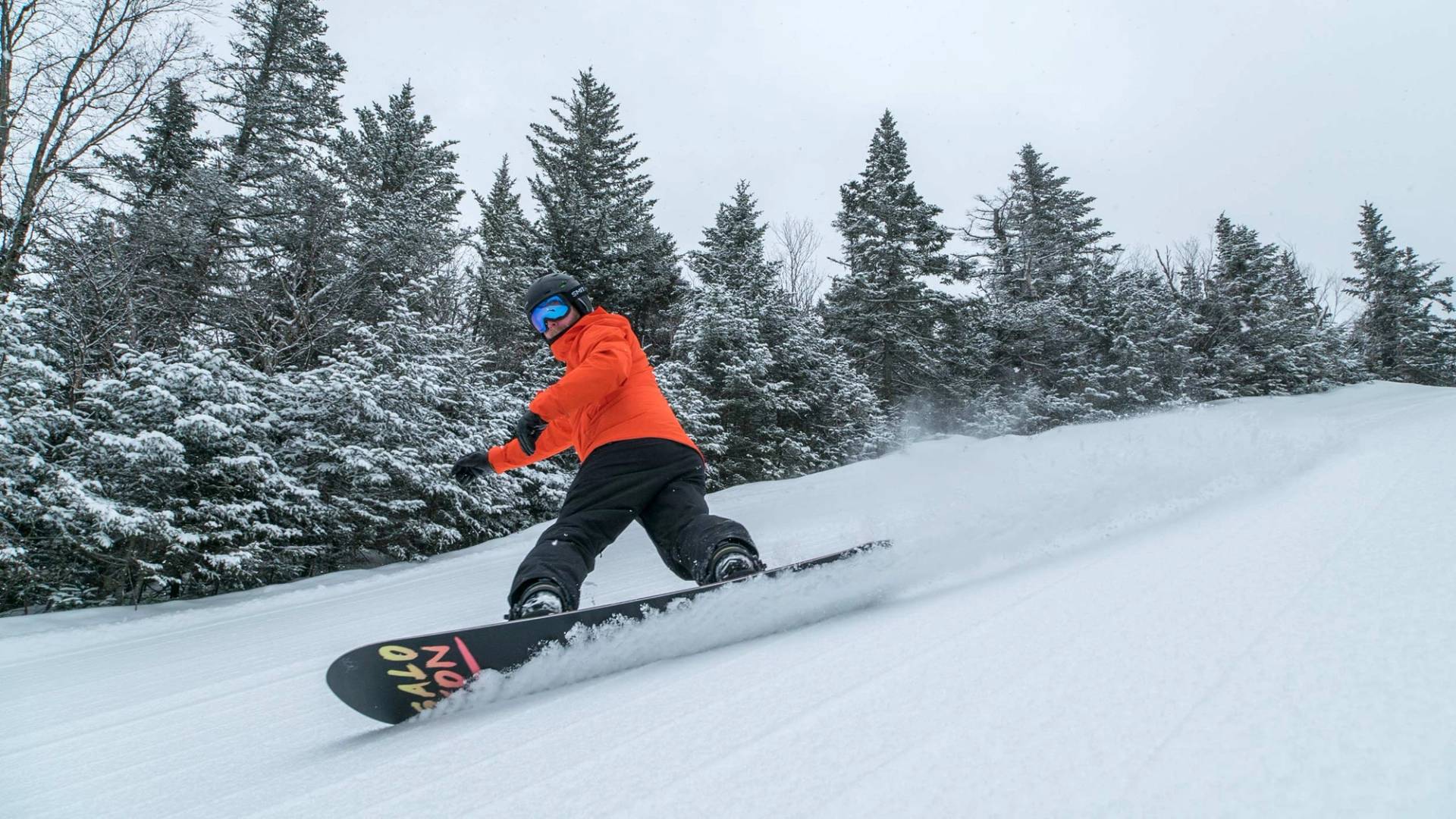 snowboarder in orange jacket making a turn