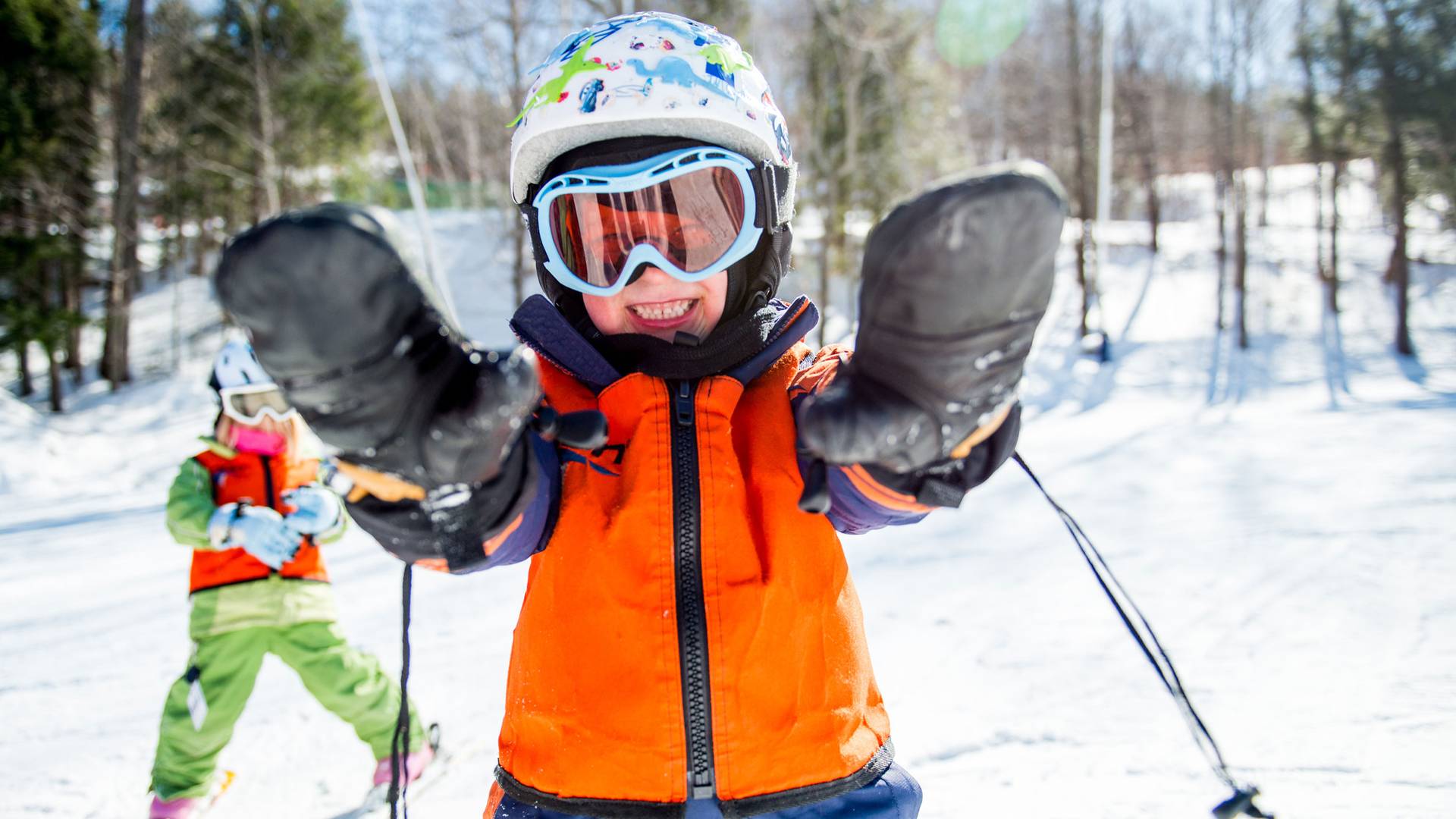 Kid reaching out with mittens on while skiing at Loon Mountain