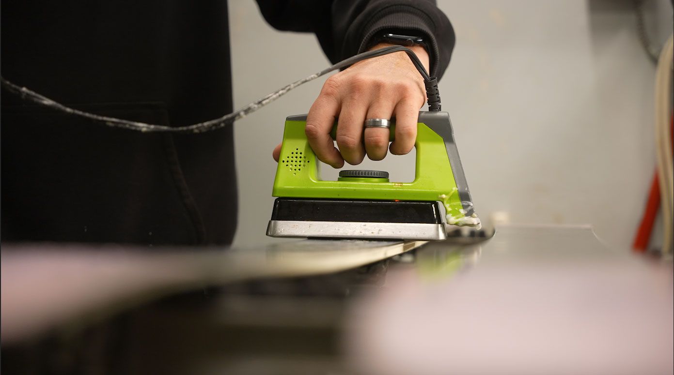 hot wax being applied to ski bottom