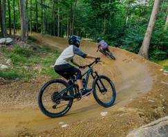 2 bikers going around a berm in the summer