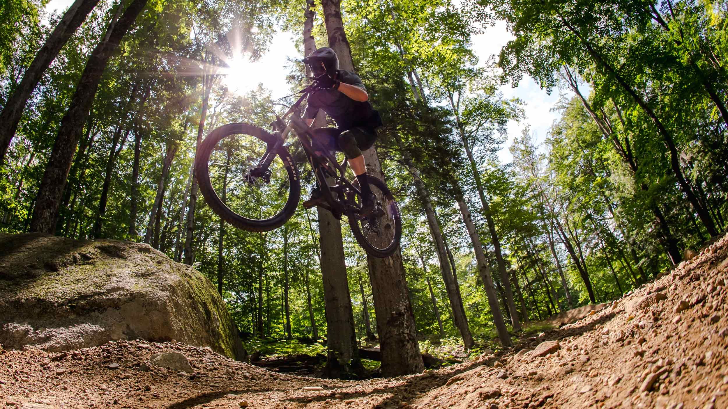 Downhill mountain bike rider jumping off a rock feature