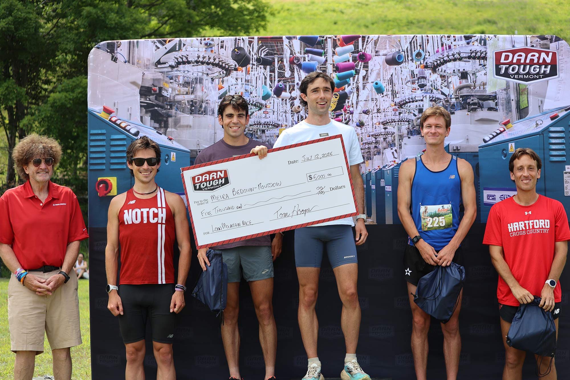 male winner on podium holding Darn Tough prize check