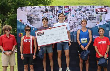 male winner on podium holding Darn Tough prize check