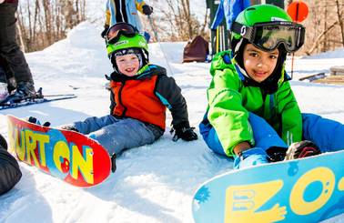 two young snowboarders sitting on the snow