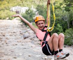 girl riding the zipline across the Pemi River