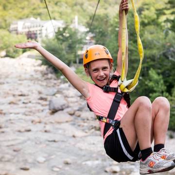 girl riding the zipline across the Pemi River