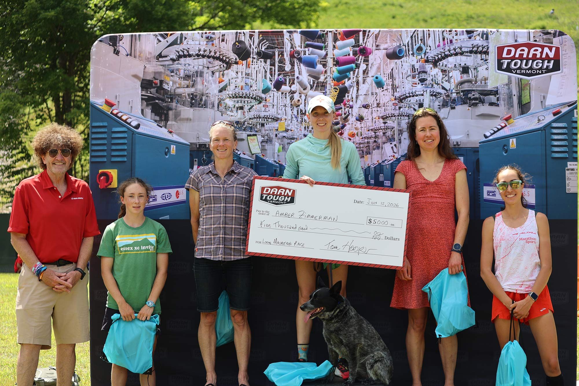 female winner on podium holding Darn Tough prize check