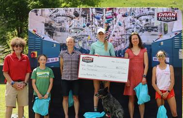 female winner on podium holding Darn Tough prize check