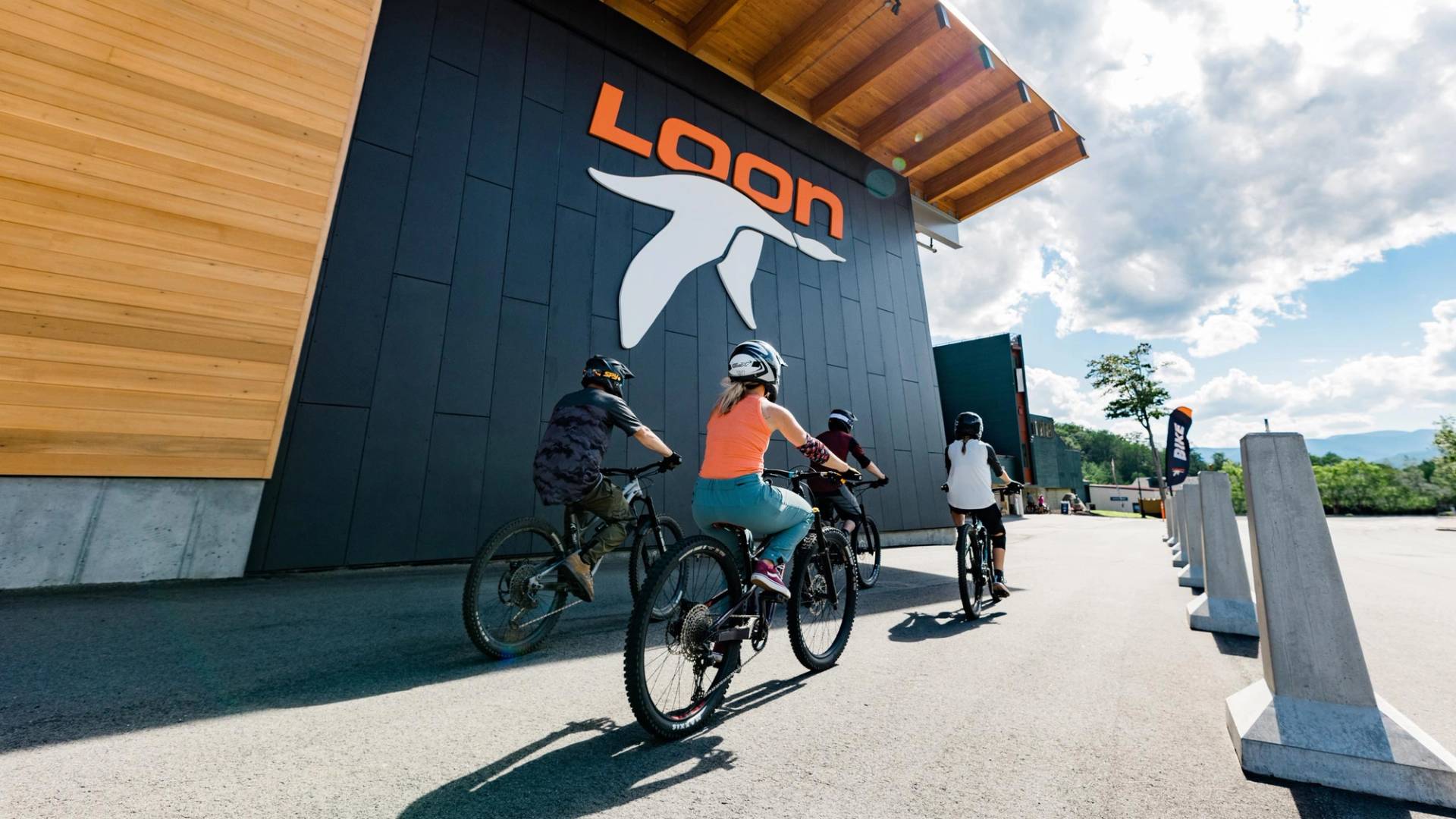 bikers riding past the exterior of the Kancamagus 8 parking garage