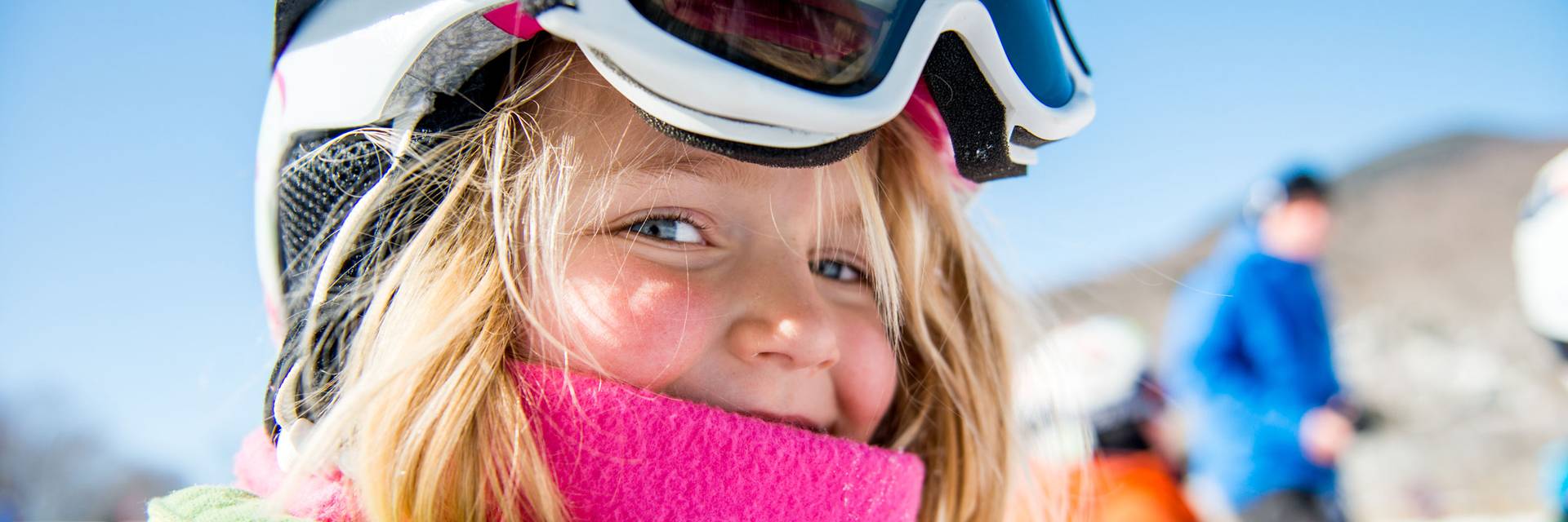 smiling young girl wearing a pink neck gaitor and helmet