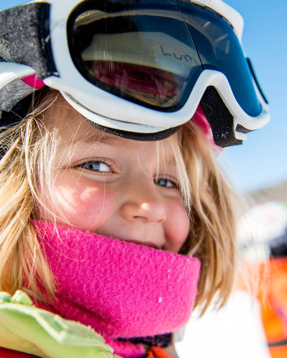Smiling little girl wearing ski helmet and goggles