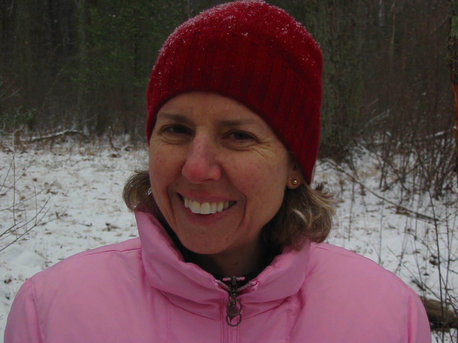 woman in red hat and pink jacket smiling at the camera
