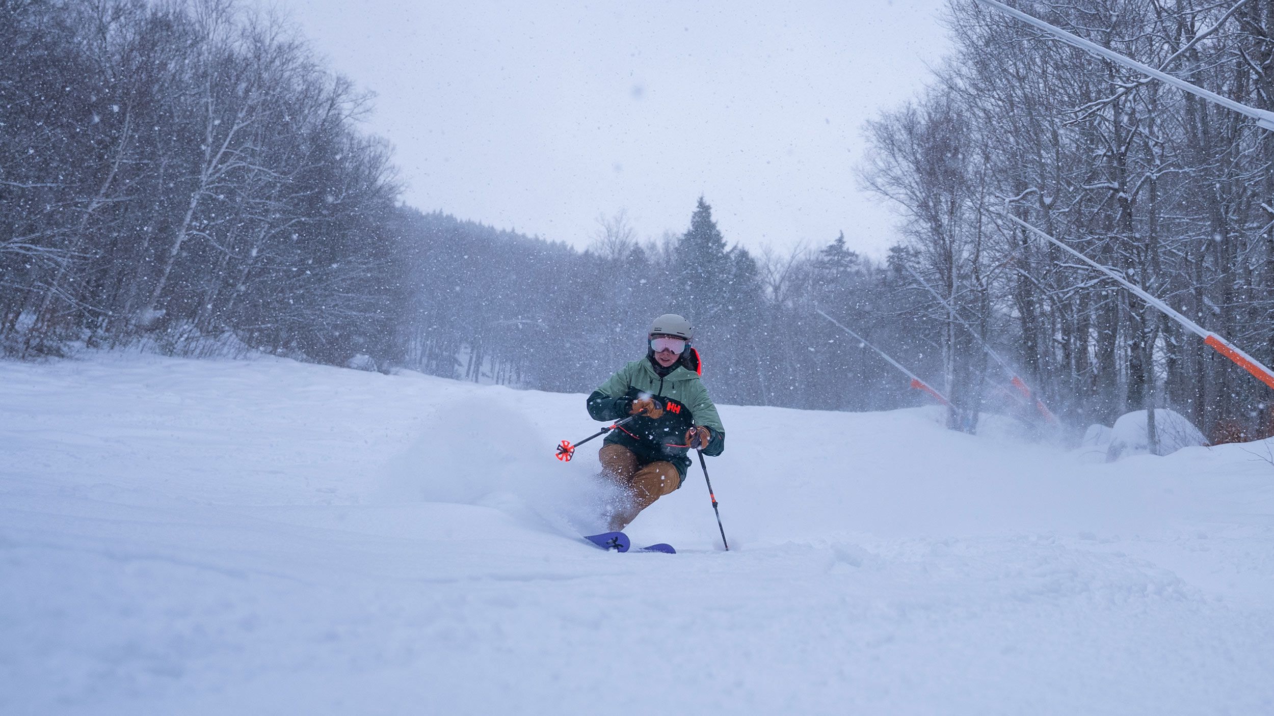 skier in powder with snow falling and snow guns in the background