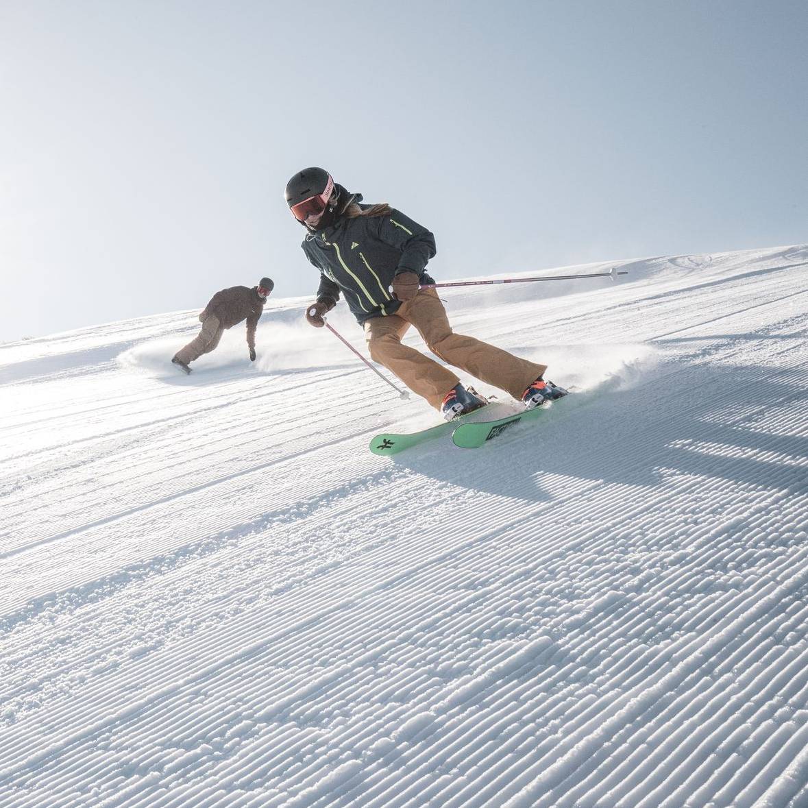 Skier and snowboarder on a groomed run