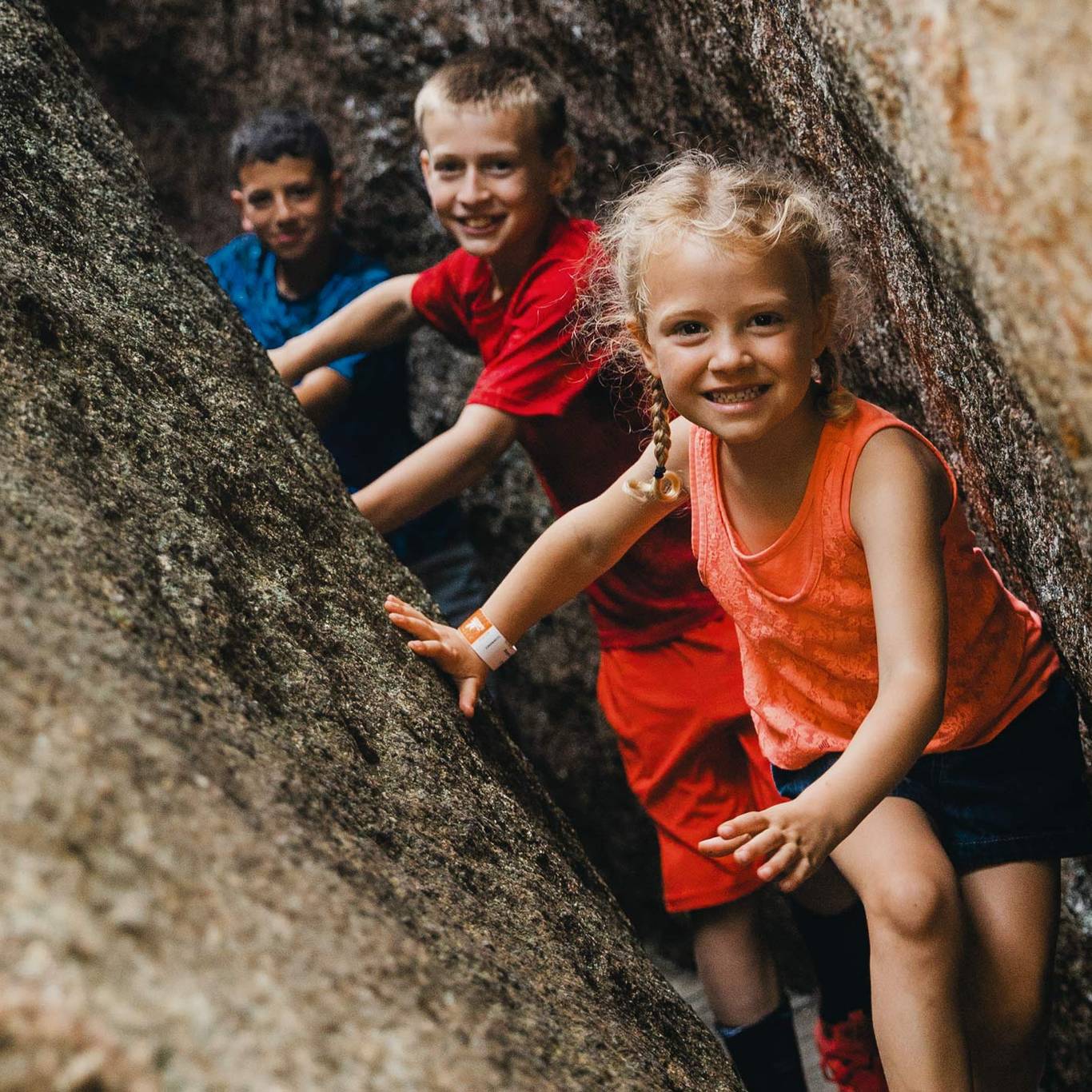 Kids squeezing between granite boulders