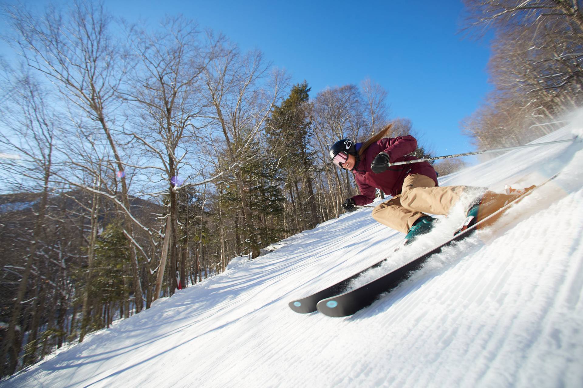 Skiers on the Jordan 8 chair at Sunday River with mountains in the background.