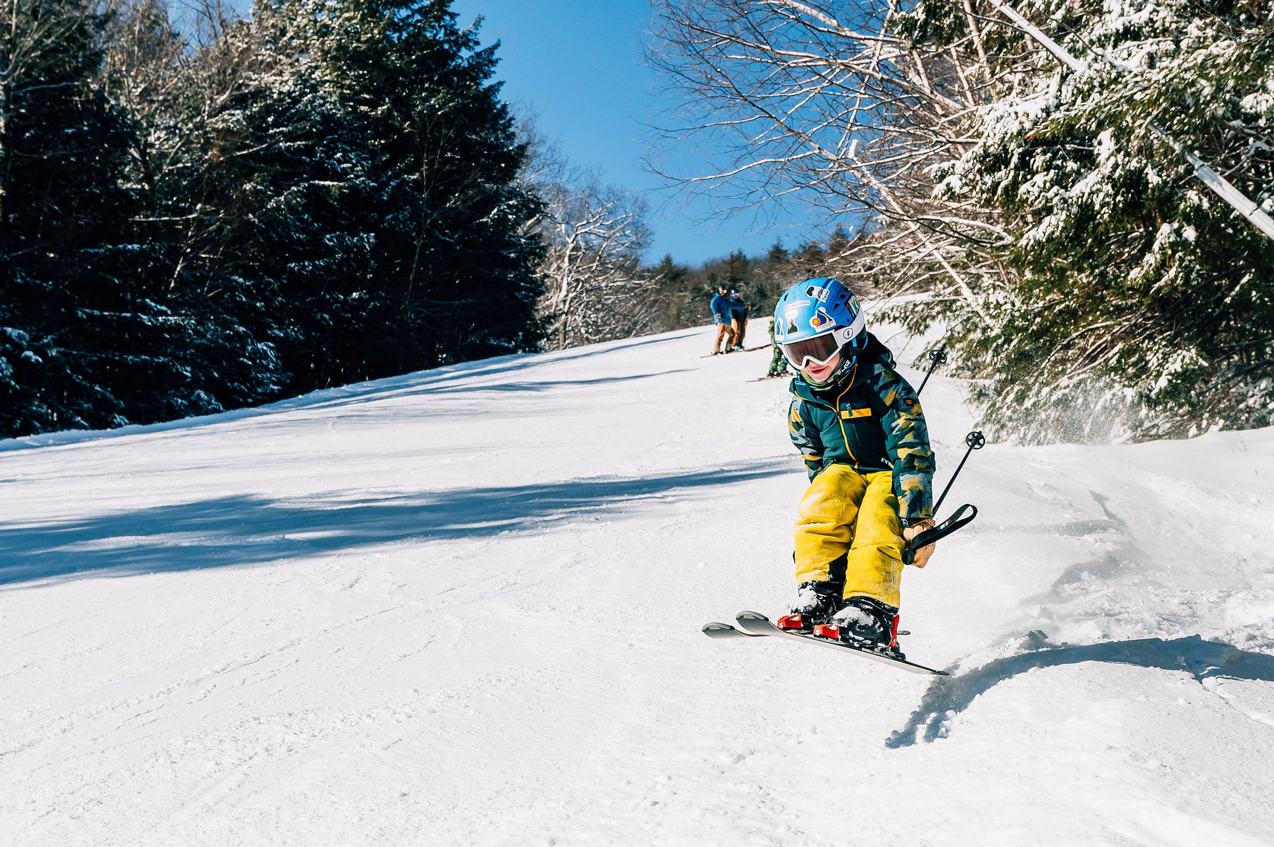 Kids jumping over a snowy kicker