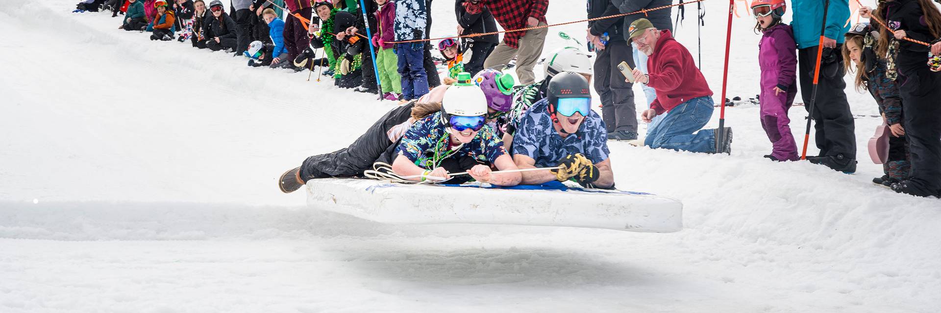 Racers sail across the finish line on a full-sized mattress.