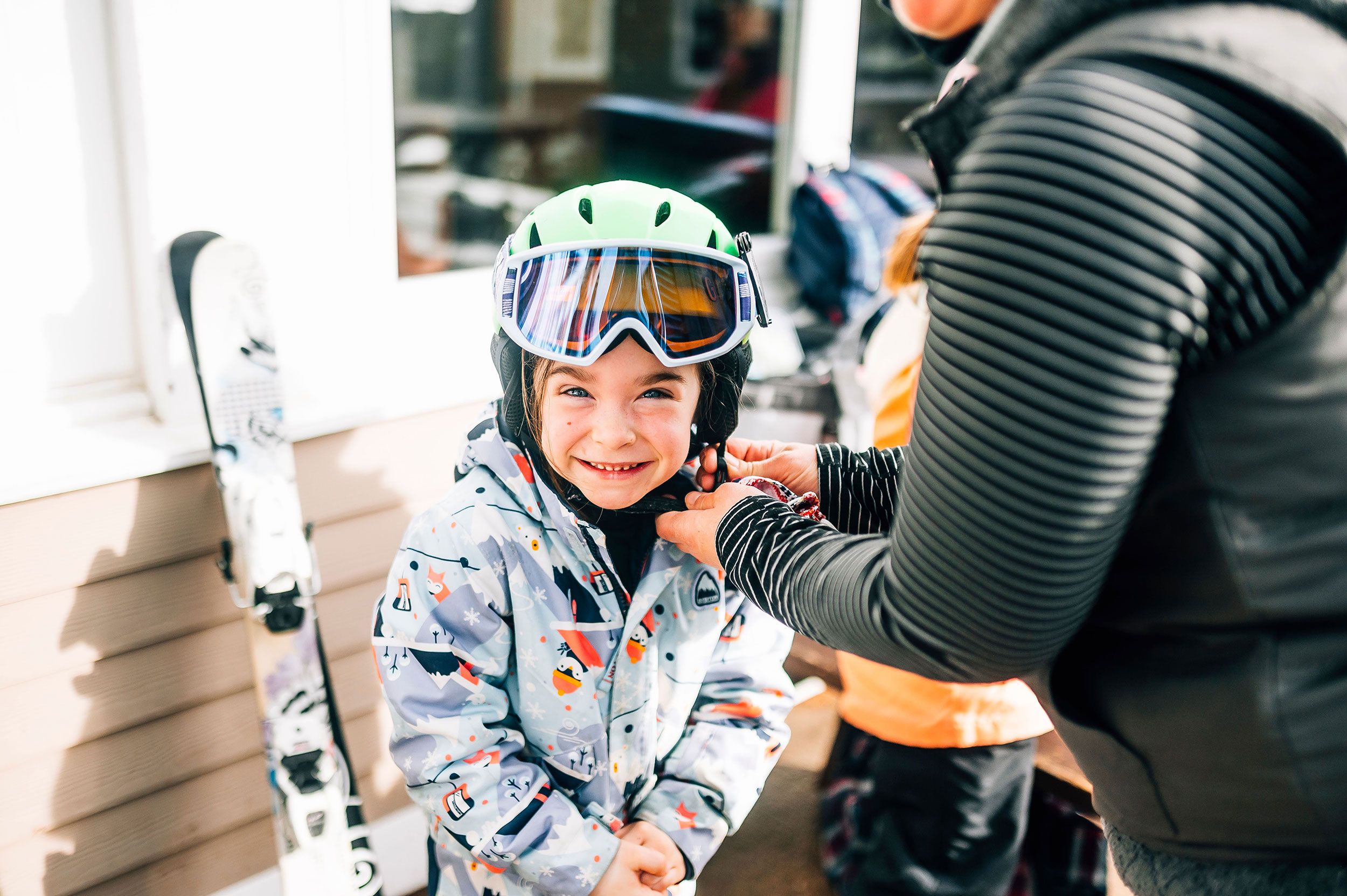 Mom helps little girl buckle her helmet