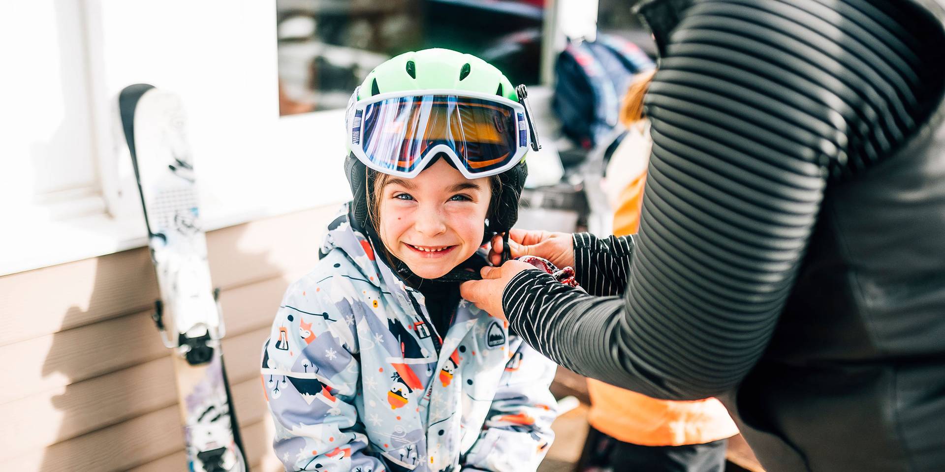 Mom helps little girl buckle her helmet