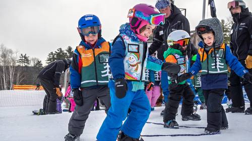 Childrens learning skills without their skis on the snow