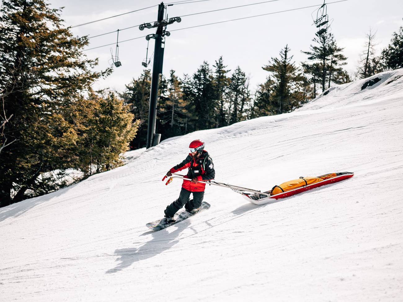 Patroller snowboards down the mountain with sled