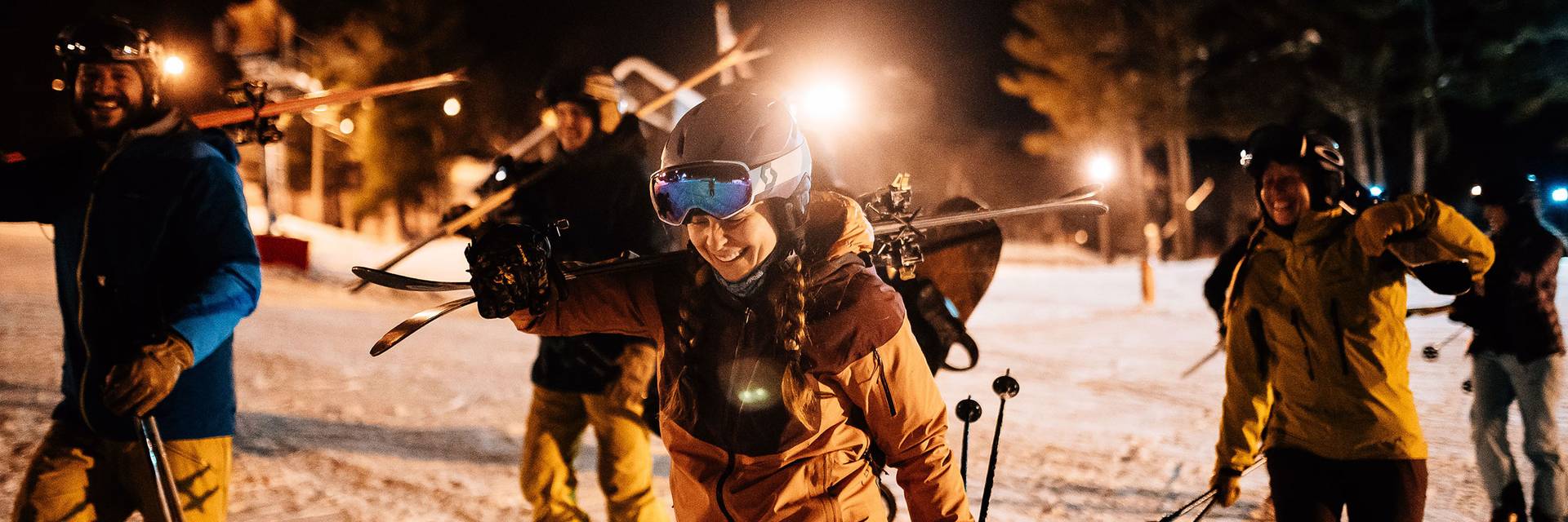 skies walk across snow to chairlift at night