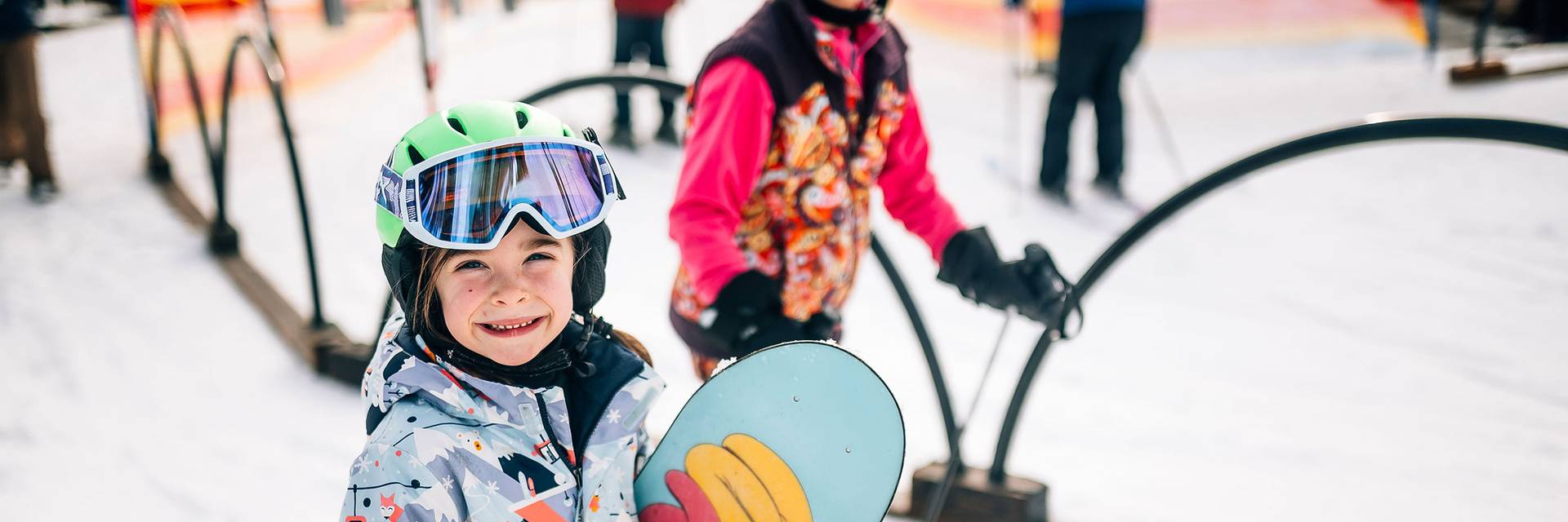 A young skier and snowboarder smiling in the lift line