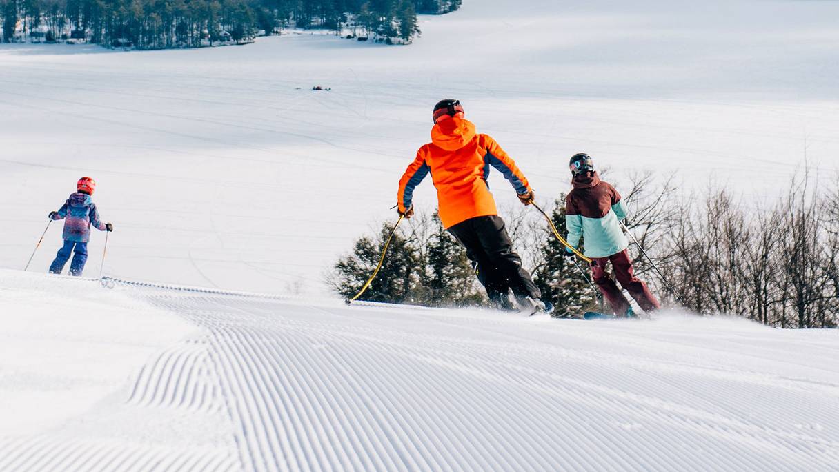 Family skis over the crest of the horn with the western foothills in the background