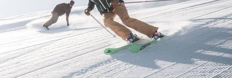 Skier and snowboarder on a groomed run