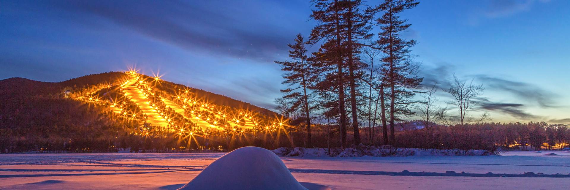 Lights twinkle on Pleasant Mountain across Moose Pond