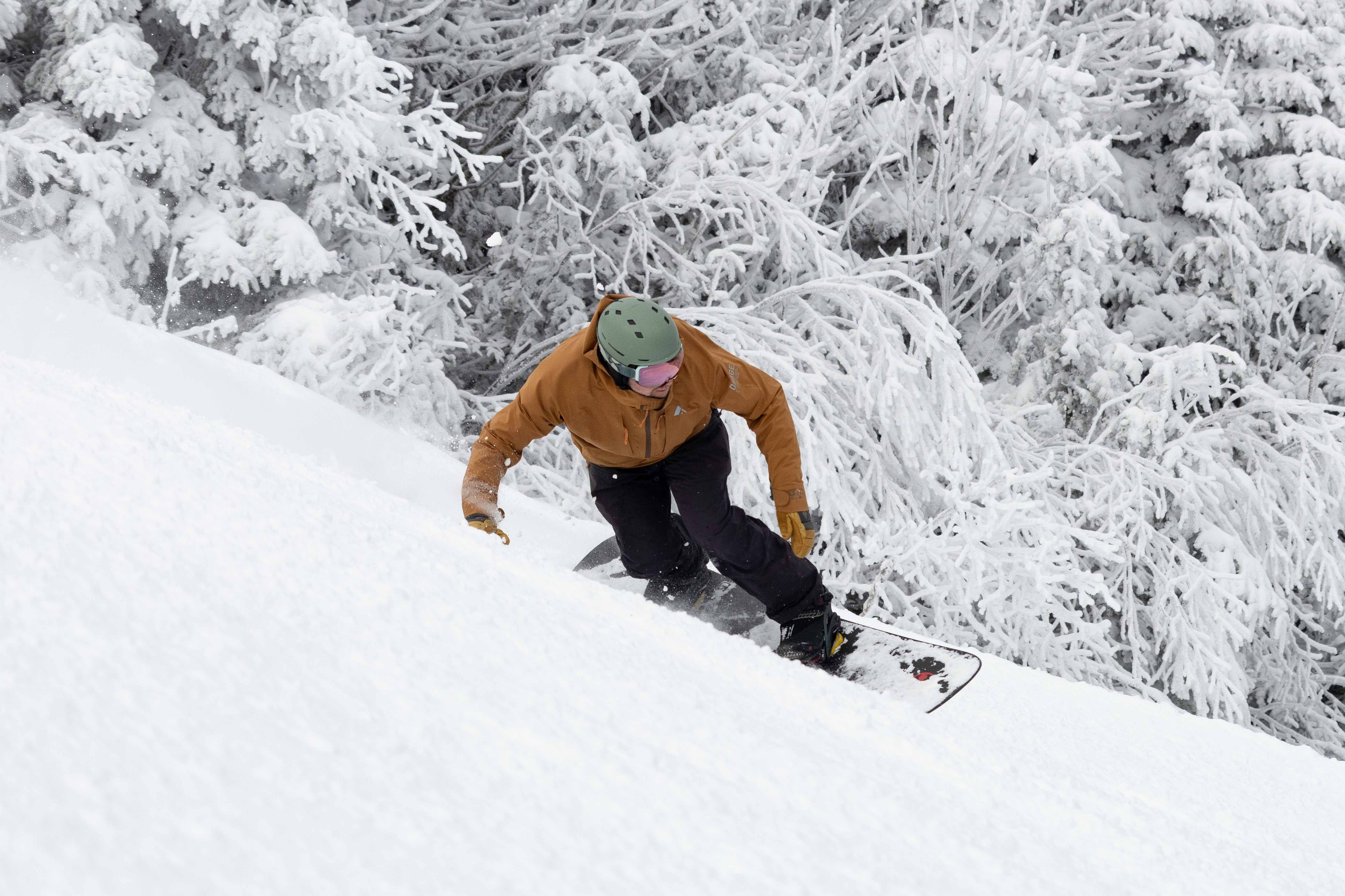 Snowboarder in a brown jacket carving deep