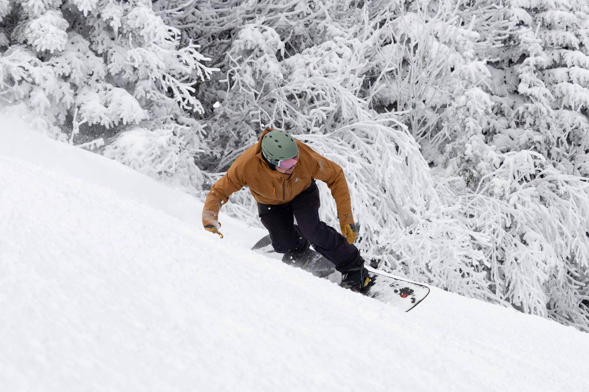 Snowboarder in a brown jacket carving deep