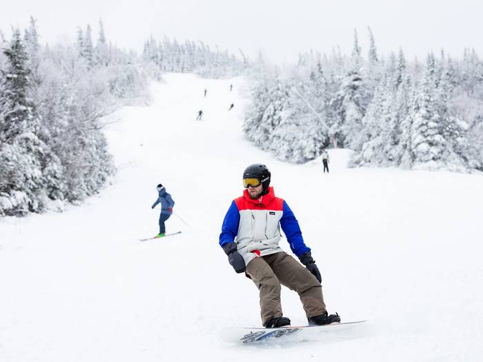 snowboarder on trail with skiers in background
