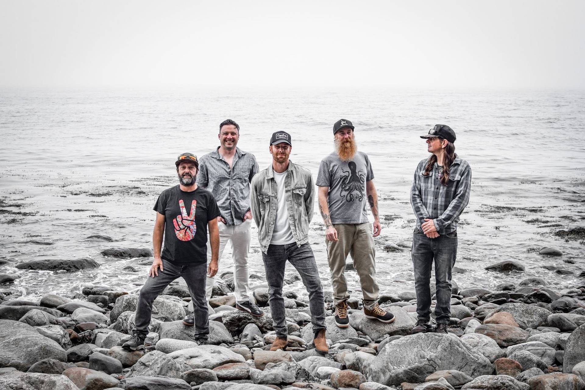 group of five men standing near ocean