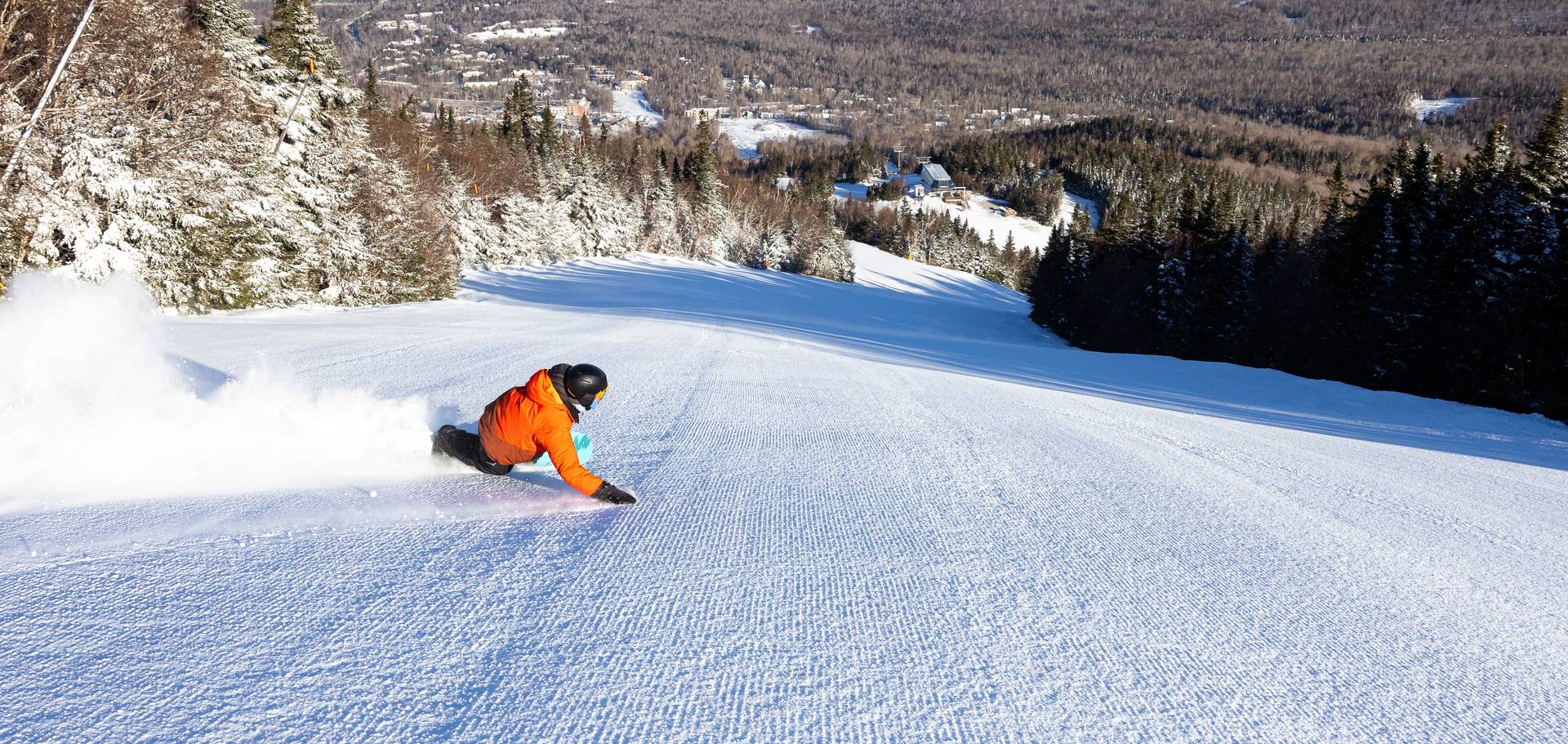 Snowboarder in orange jacket carving a turn