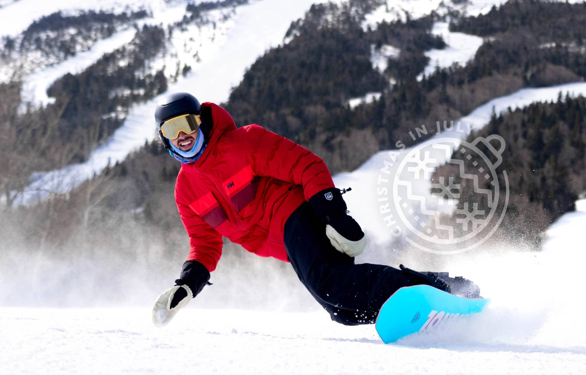 Skier in purple makes a powder turn on Hayburner with  a Christmas in July logo transparent over the shot