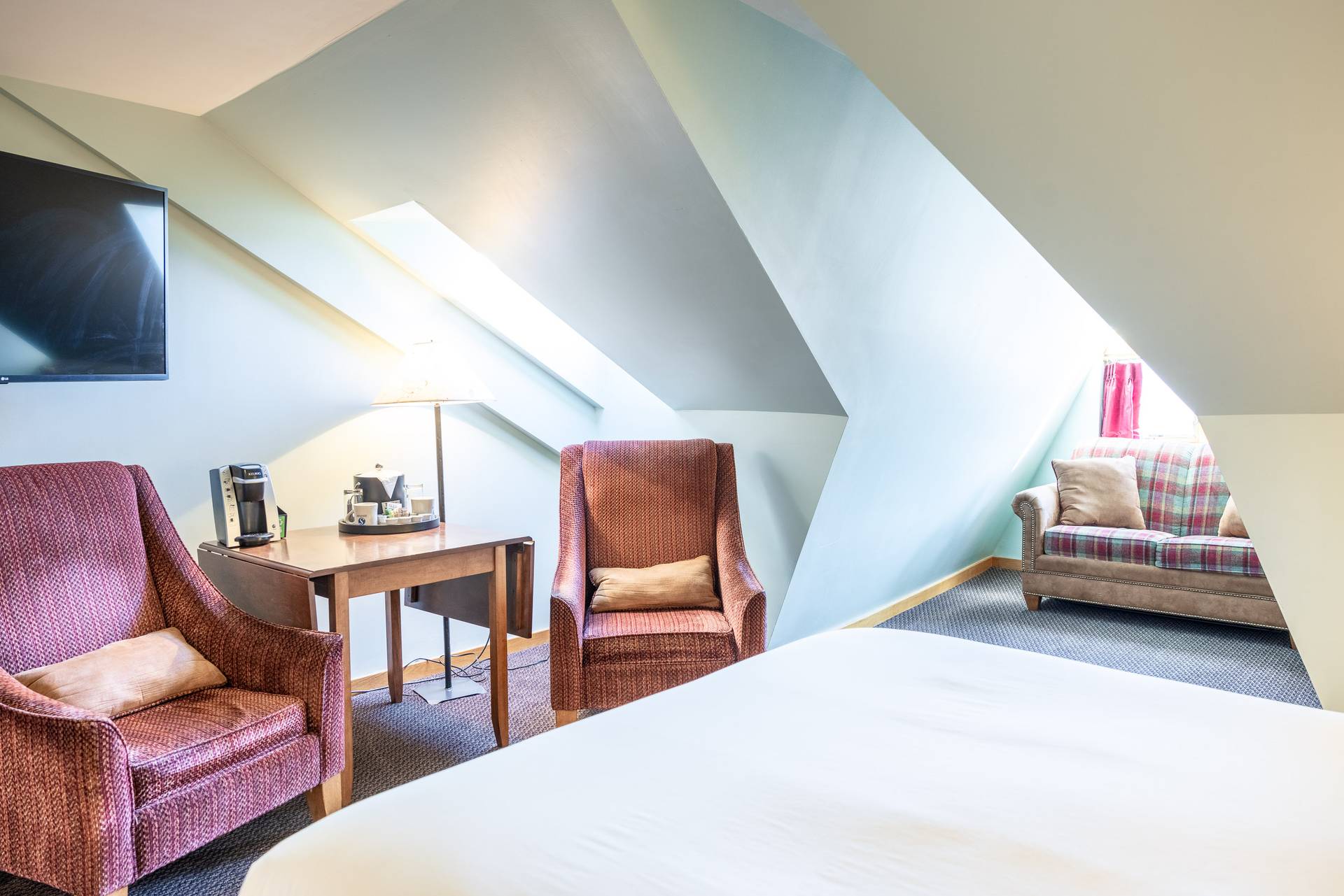 A room at the hotel featuring two inviting red chairs and a world-renowned Boyne Bed