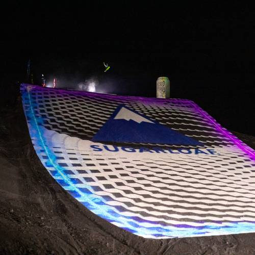 Snowboarder at the top of a large illuminated jump