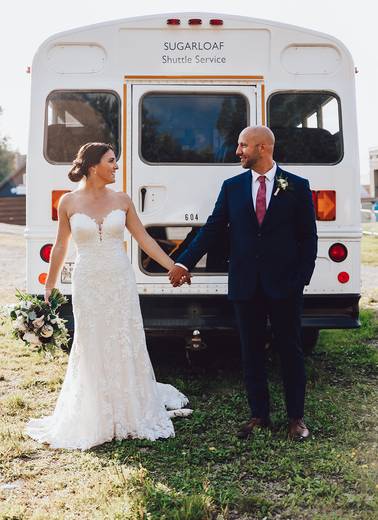 Bride and groom in front of shuttle bus