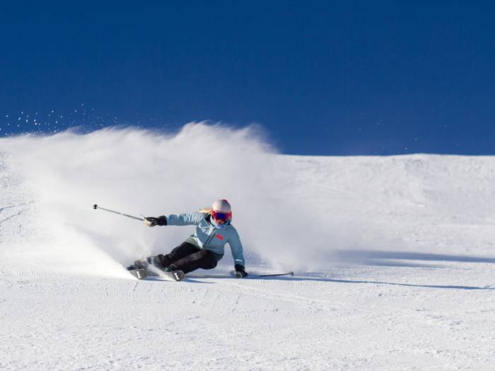 skier carving through corduroy on a bluebird day