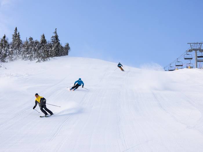 three skiers on groomed trail