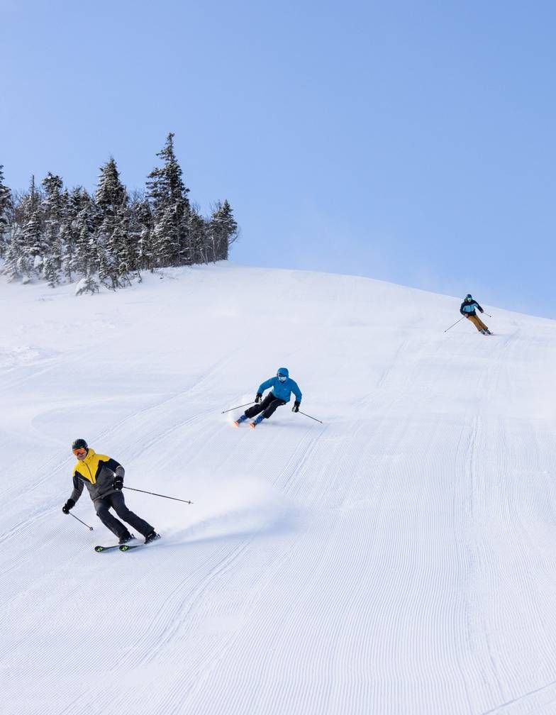 Three skiers on Sluice headwall in succession